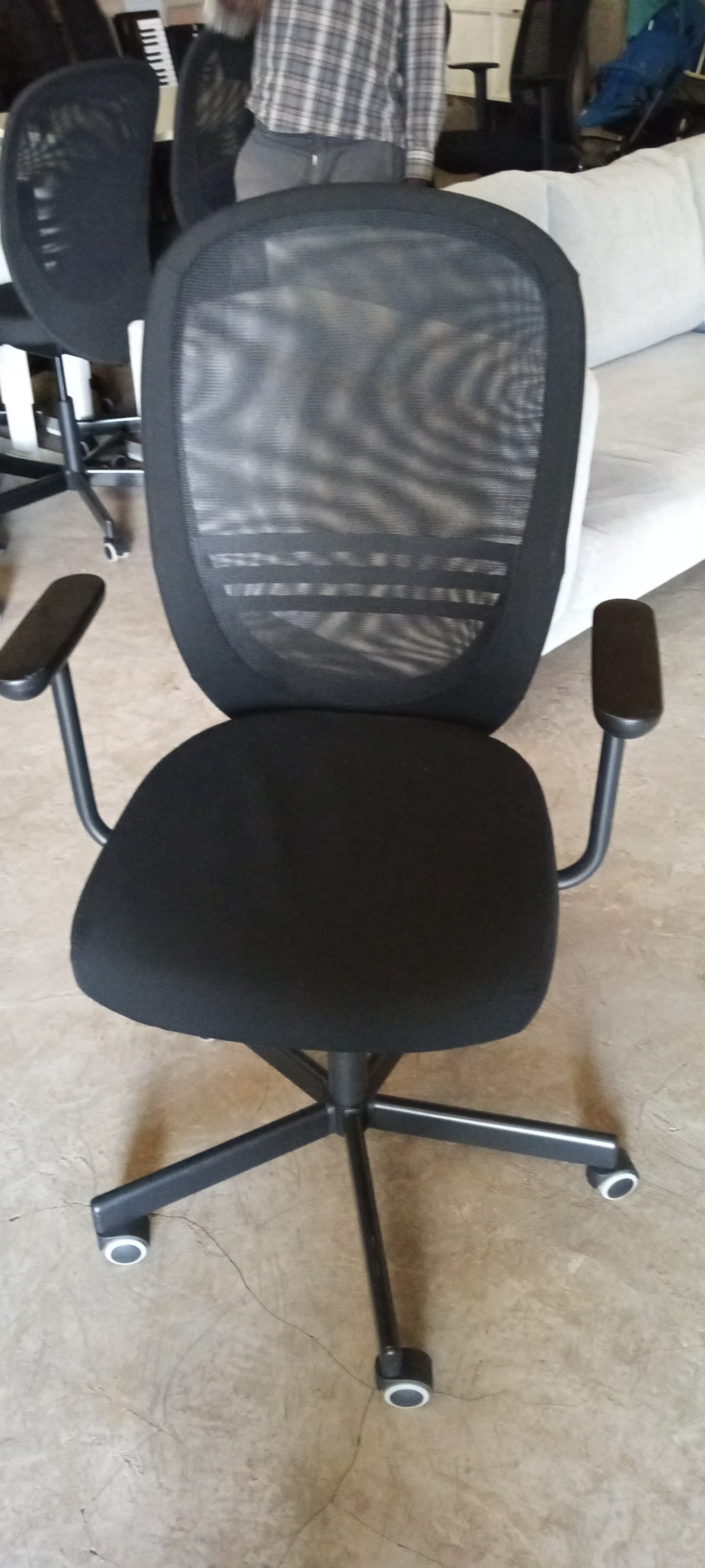 Black mesh back office chair with a padded seat and armrests on rolling wheels.